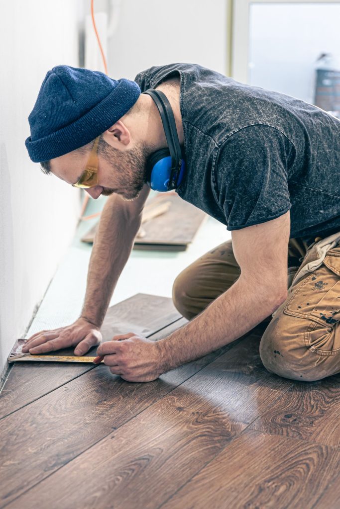 Poseur de parquet qui ajuste une lame à genoux