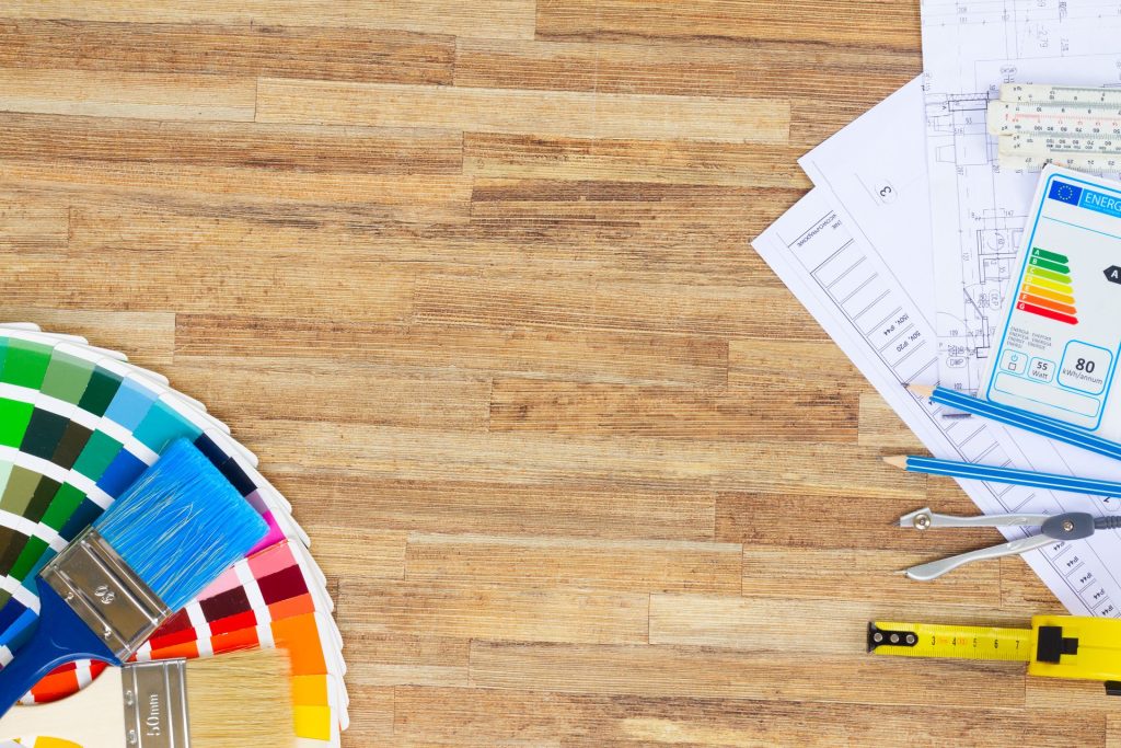 Plans, nuancier et outils posés sur un parquet pour préparer un devis